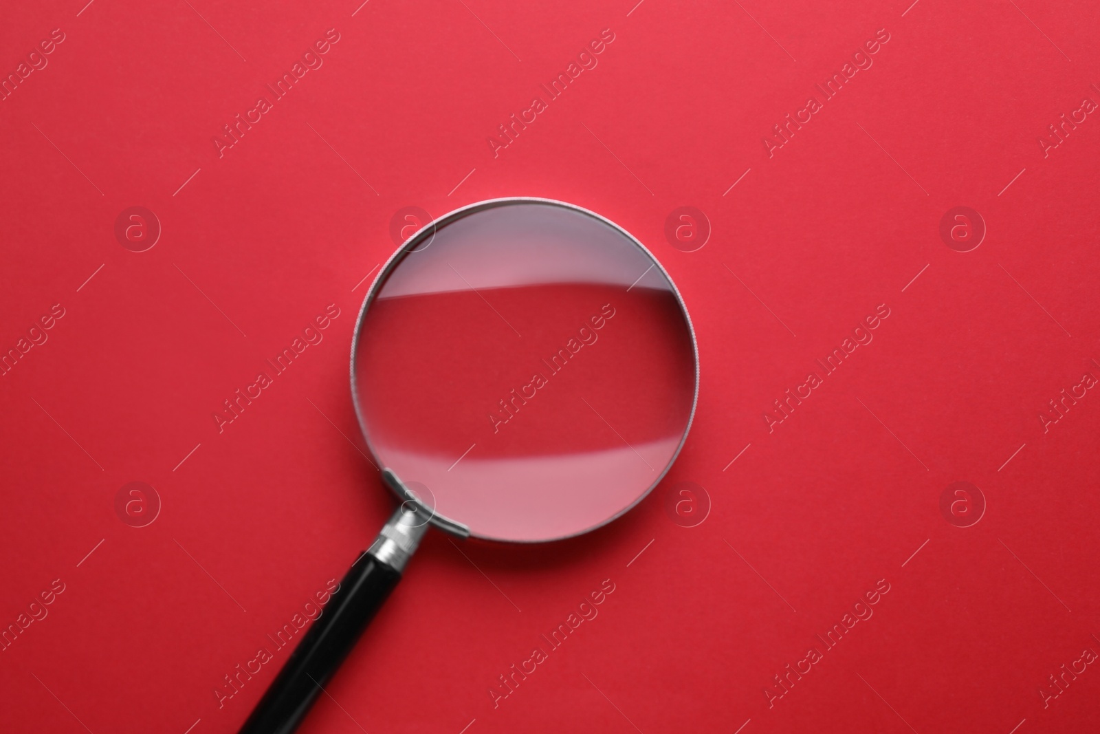 Photo of Magnifying glass on red background, top view