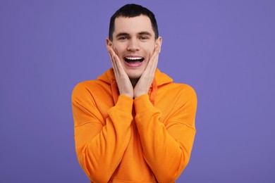Portrait of surprised man on purple background
