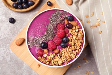 Delicious acai smoothie with granola and berries served on marble table, flat lay