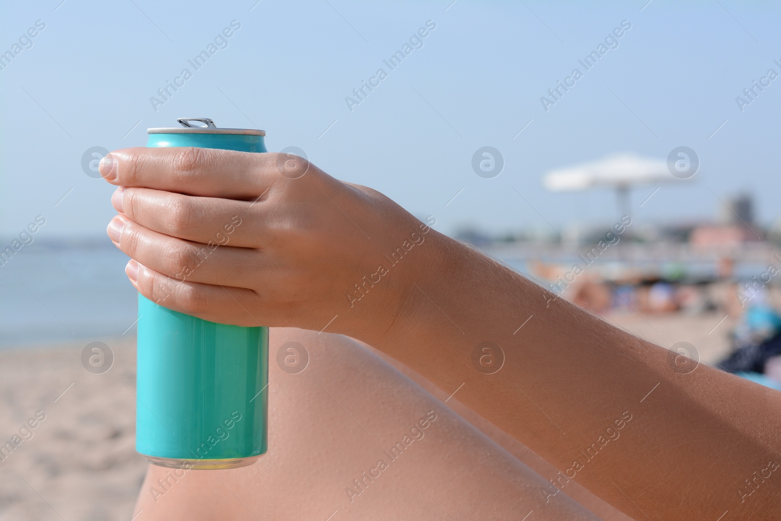 Photo of Woman holding aluminum can with beverage on beach, closeup