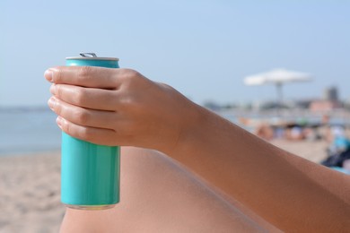 Photo of Woman holding aluminum can with beverage on beach, closeup