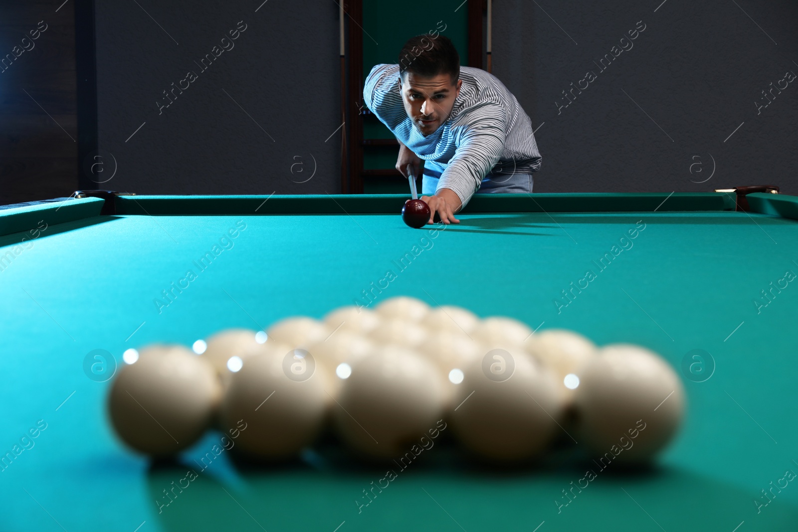 Photo of Handsome young man playing Russian billiard indoors