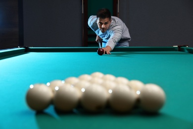 Handsome young man playing Russian billiard indoors