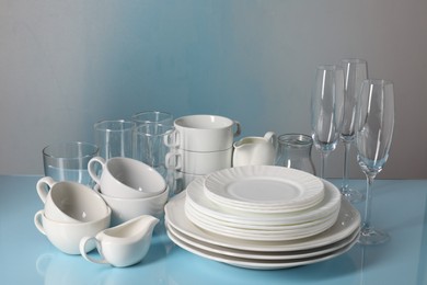 Set of clean dishes and glasses on light blue table