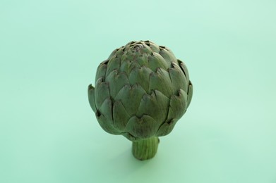 Whole fresh raw artichoke on green background, closeup