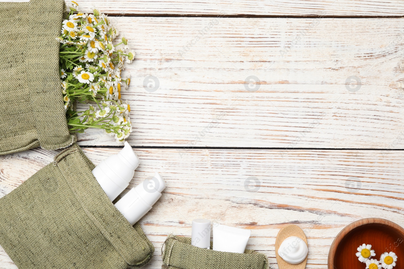 Photo of Flat lay composition with chamomile flowers and cosmetic products on white wooden table, space for text