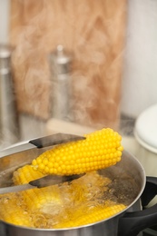 Taking corn cob from stewpot with boiling water, closeup. Space for text