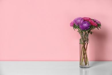 Beautiful flowers in vase and space for text on color background. Element of interior design