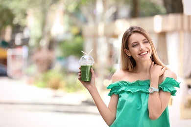 Young woman with plastic cup of healthy smoothie outdoors