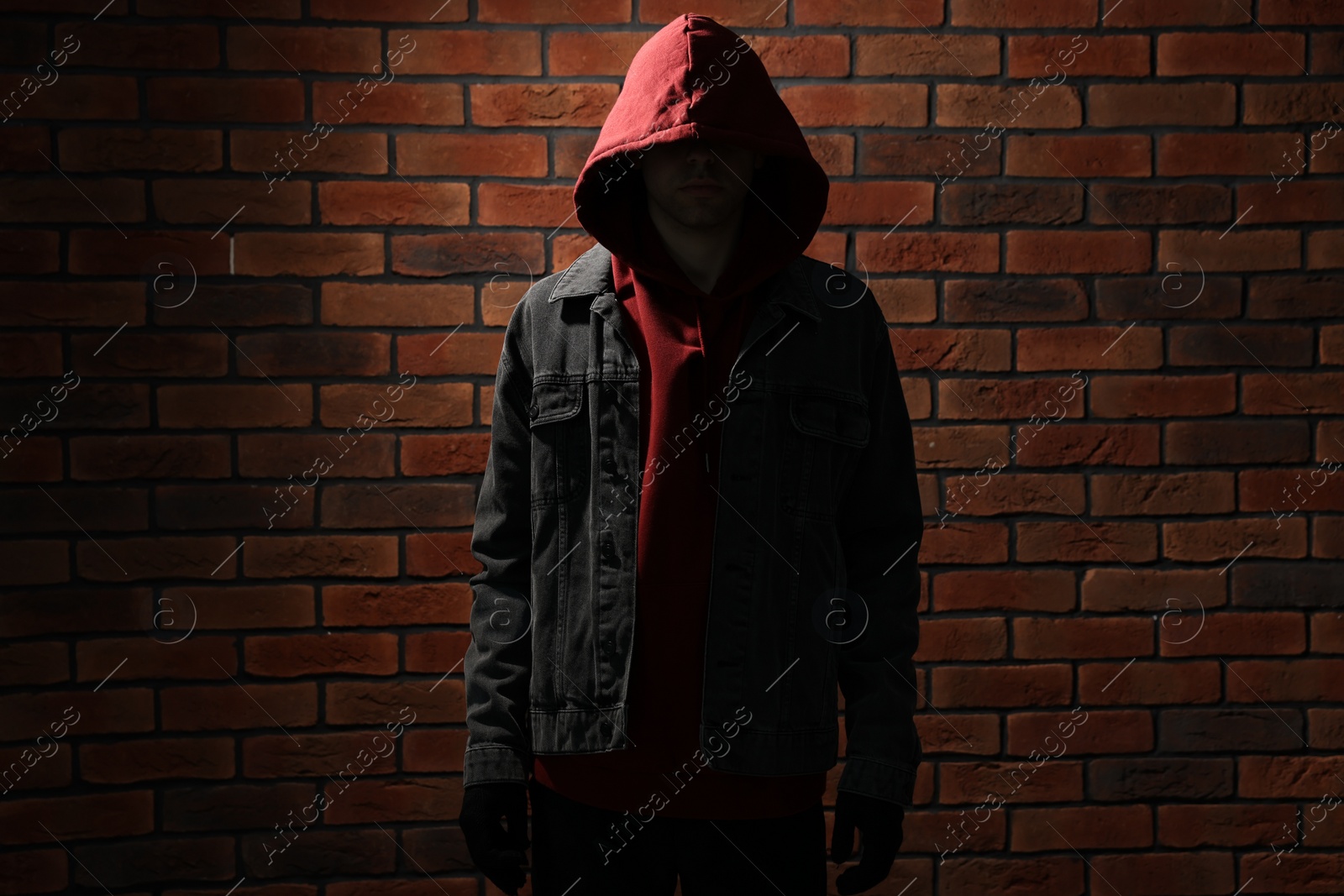 Photo of Thief in hoodie against red brick wall