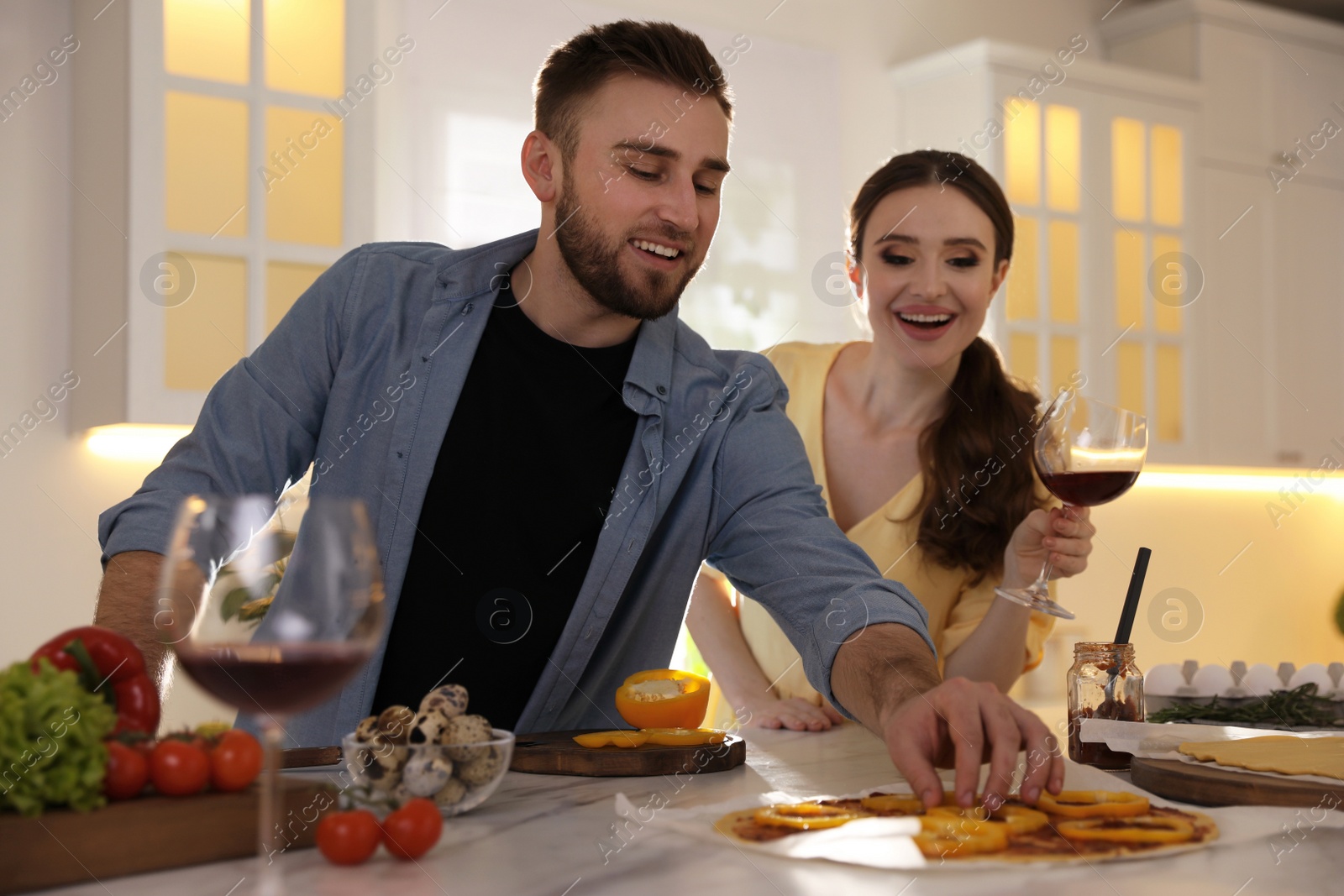 Photo of Lovely young couple cooking pizza together in kitchen