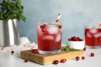 Photo of Tasty refreshing cranberry cocktail with mint on white table