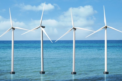 Image of Floating wind turbines installed in water under blue sky. Alternative energy source