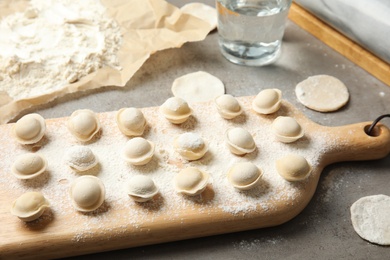 Photo of Board with raw dumplings on table. Process of cooking