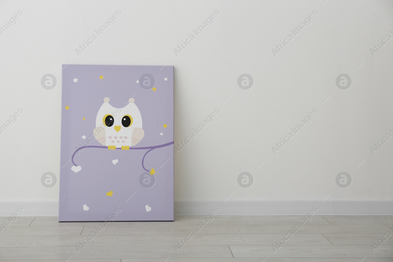Photo of Adorable picture of owl on floor near white wall, space for text. Children's room interior element