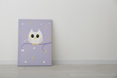 Adorable picture of owl on floor near white wall, space for text. Children's room interior element