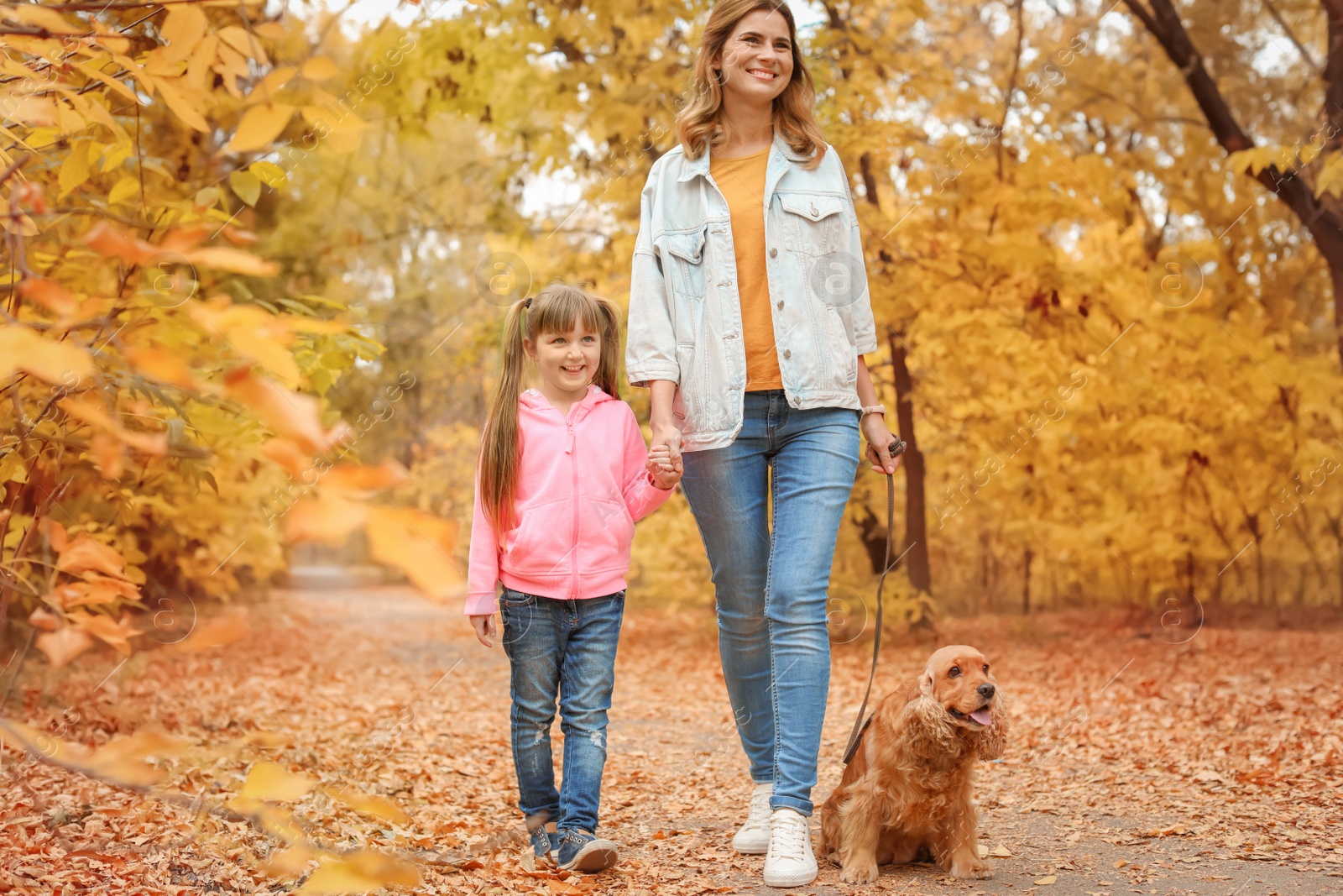 Photo of Mother with her cute daughter and dog in park. Autumn walk