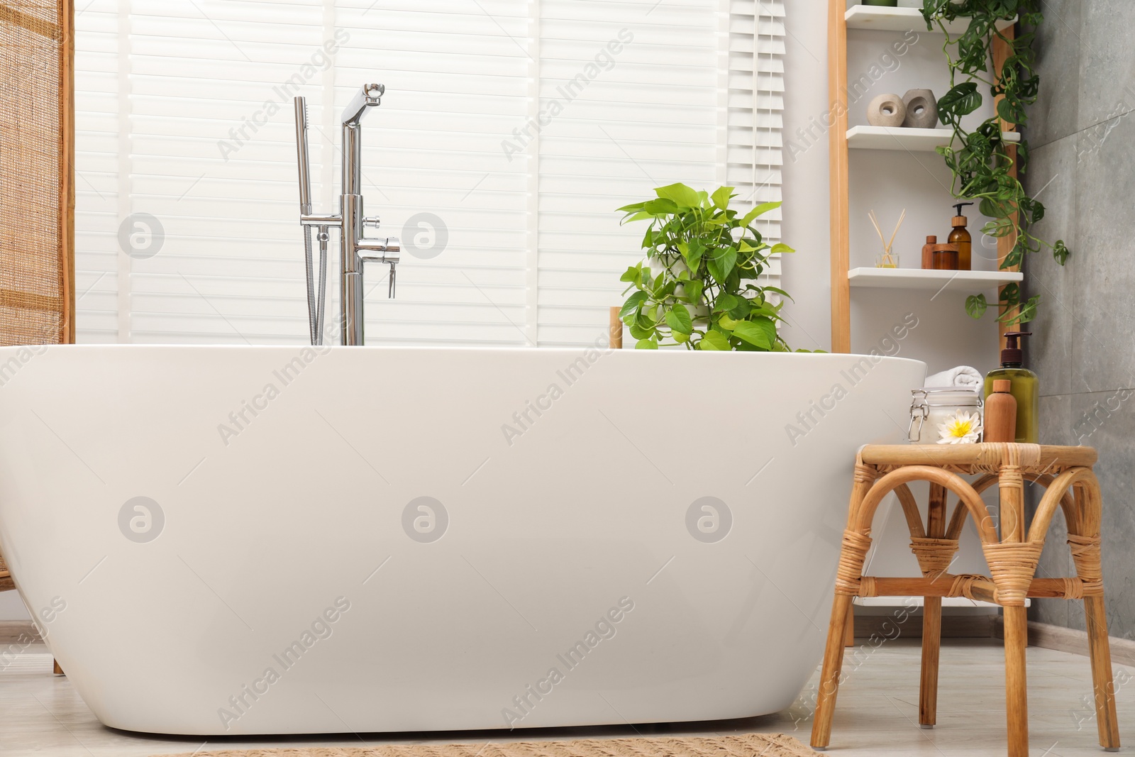 Photo of Stylish bathroom interior with ceramic tub, spa products and green houseplants