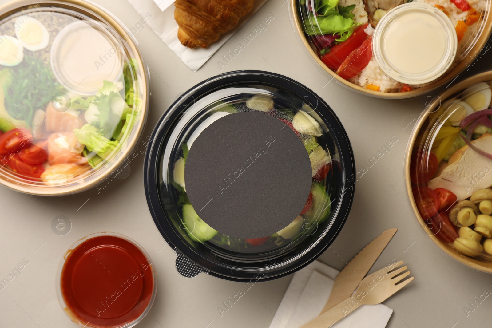 Photo of Tasty food in containers with wooden knife and fork on light grey table, flat lay. Space for text