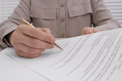 Woman signing document with pen, closeup view