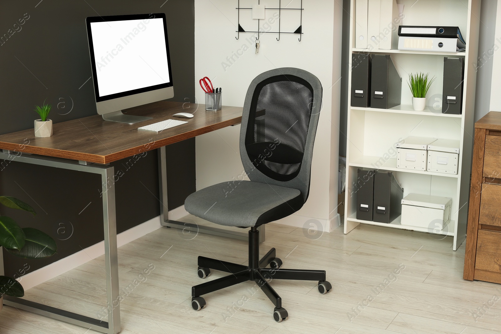 Photo of Stylish office interior with comfortable chair, desk and computer