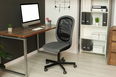 Stylish office interior with comfortable chair, desk and computer