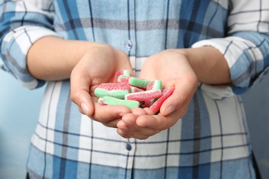 Young woman holding handful of tasty jelly candies, closeup