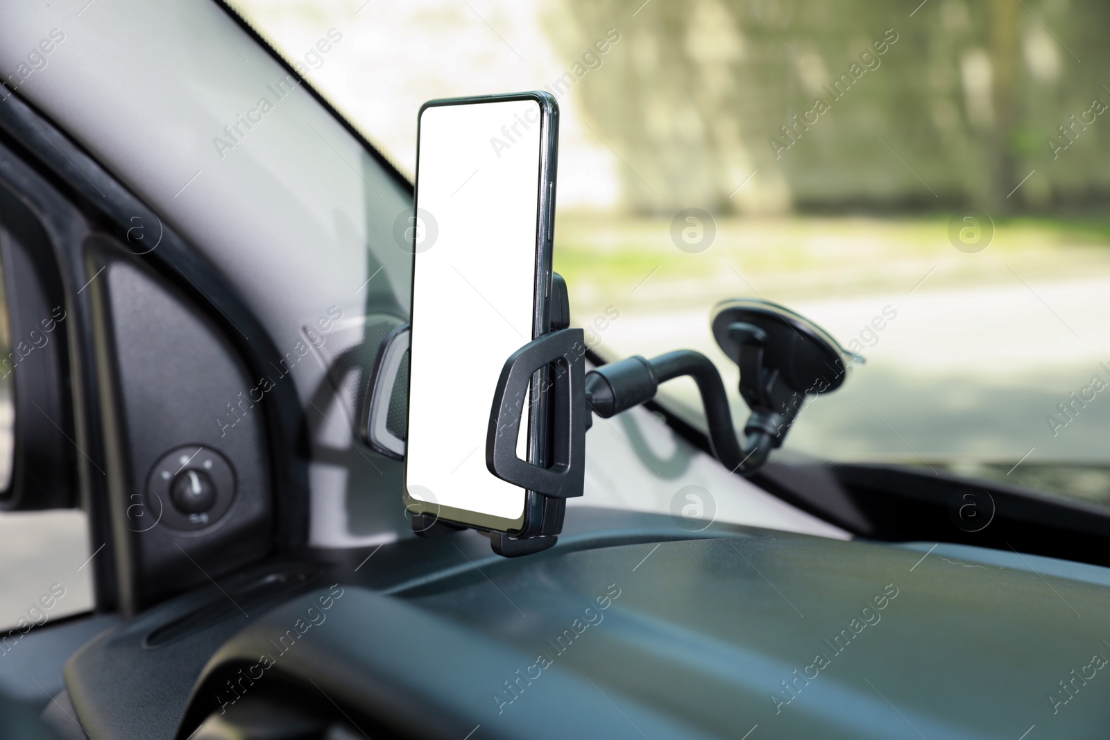 Photo of Car holder with modern mobile phone on windshield of automobile. Mockup for design