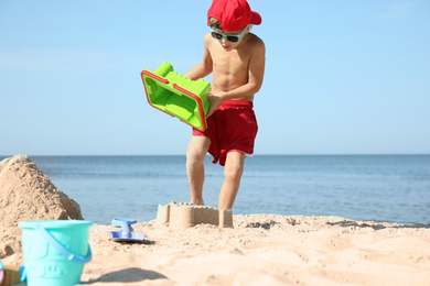 Cute little child playing with plastic toys at sandy beach on sunny day