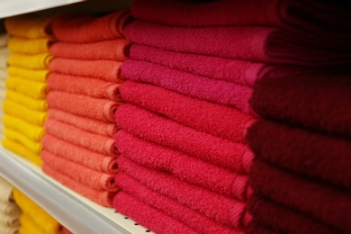 Photo of Stacks of colourful towels on store shelf, closeup