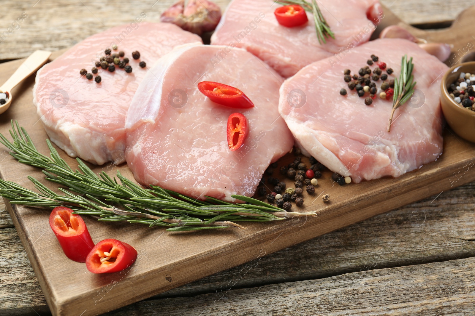 Photo of Pieces of raw pork meat and spices on wooden table, closeup