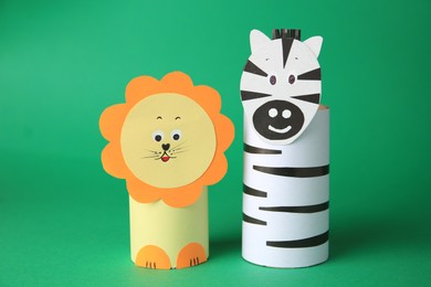 Photo of Toy lion and zebra made from toilet paper hubs on green background. Children's handmade ideas