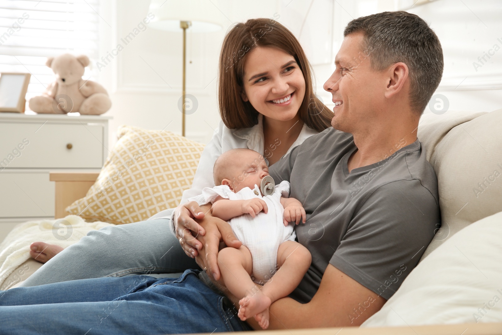 Photo of Happy couple holding their sleeping baby at home