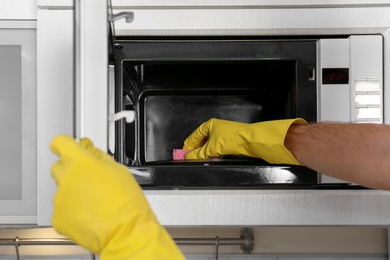 Man cleaning microwave oven in kitchen, closeup