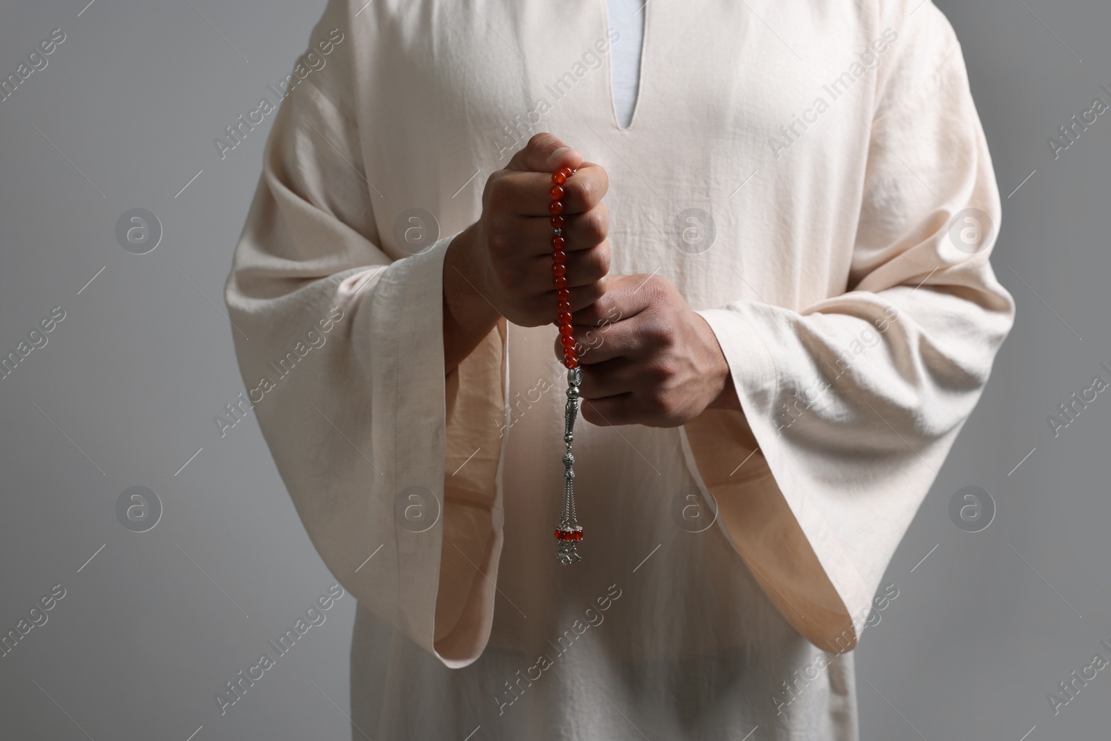 Photo of Muslim man with misbaha on light grey background, closeup