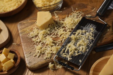 Photo of Different types of cheese and grater on wooden table, closeup