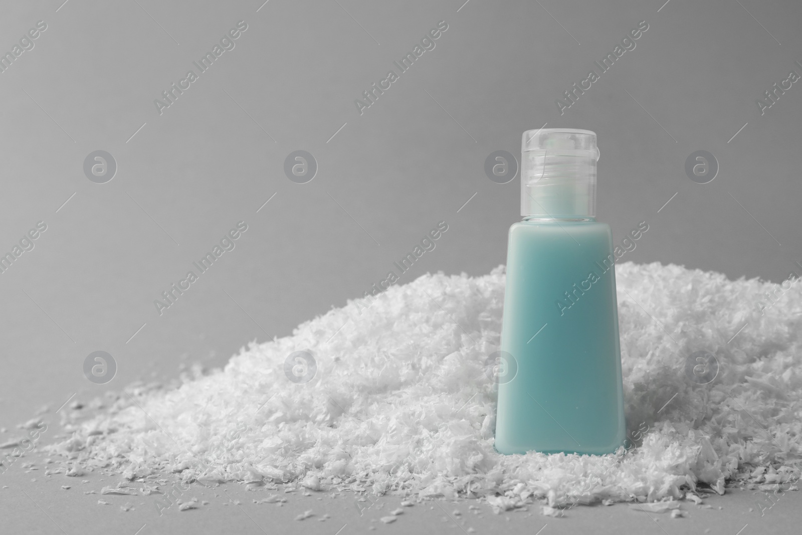 Photo of Winter skin care. Hand cream on artificial snow against light grey background, space for text