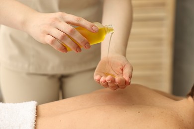 Photo of Aromatherapy. Woman receiving back massage with oil in spa salon, closeup