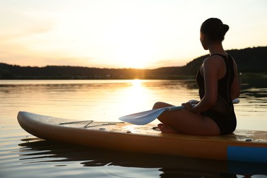 Photo of Woman paddle boarding on SUP board in river at sunset