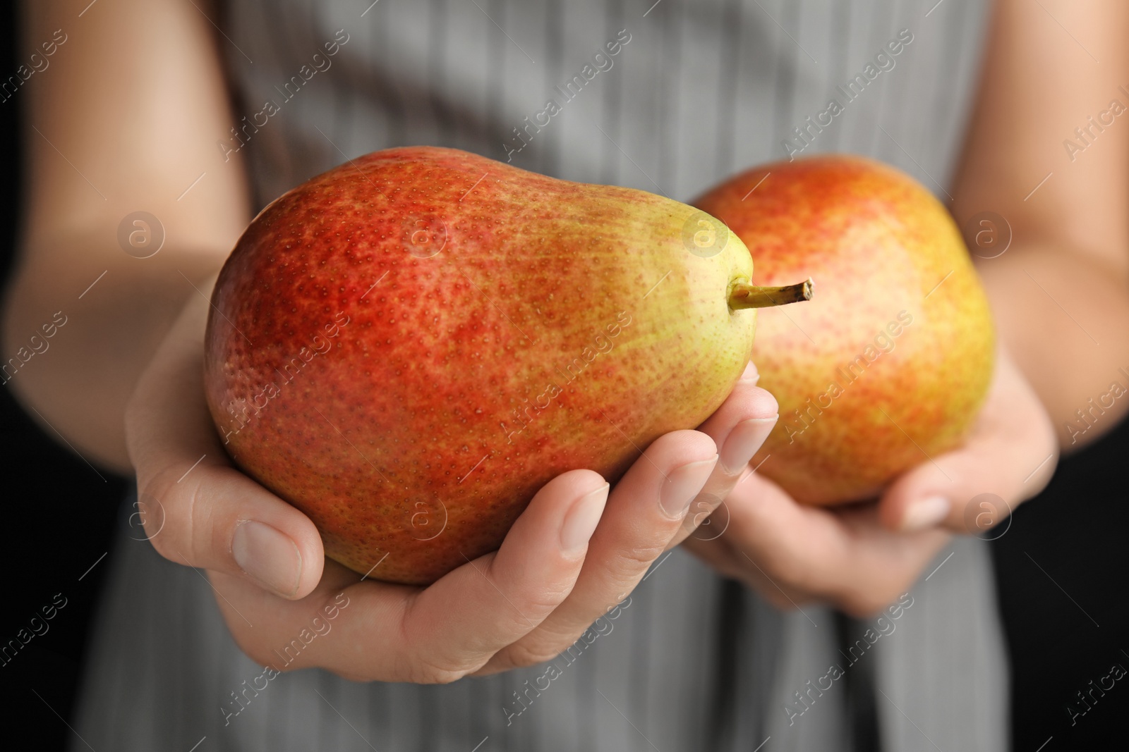 Photo of Woman holding ripe juicy pears on black background, closeup