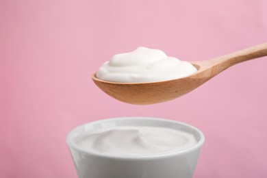 Photo of Eating delicious natural yogurt on pink background, closeup