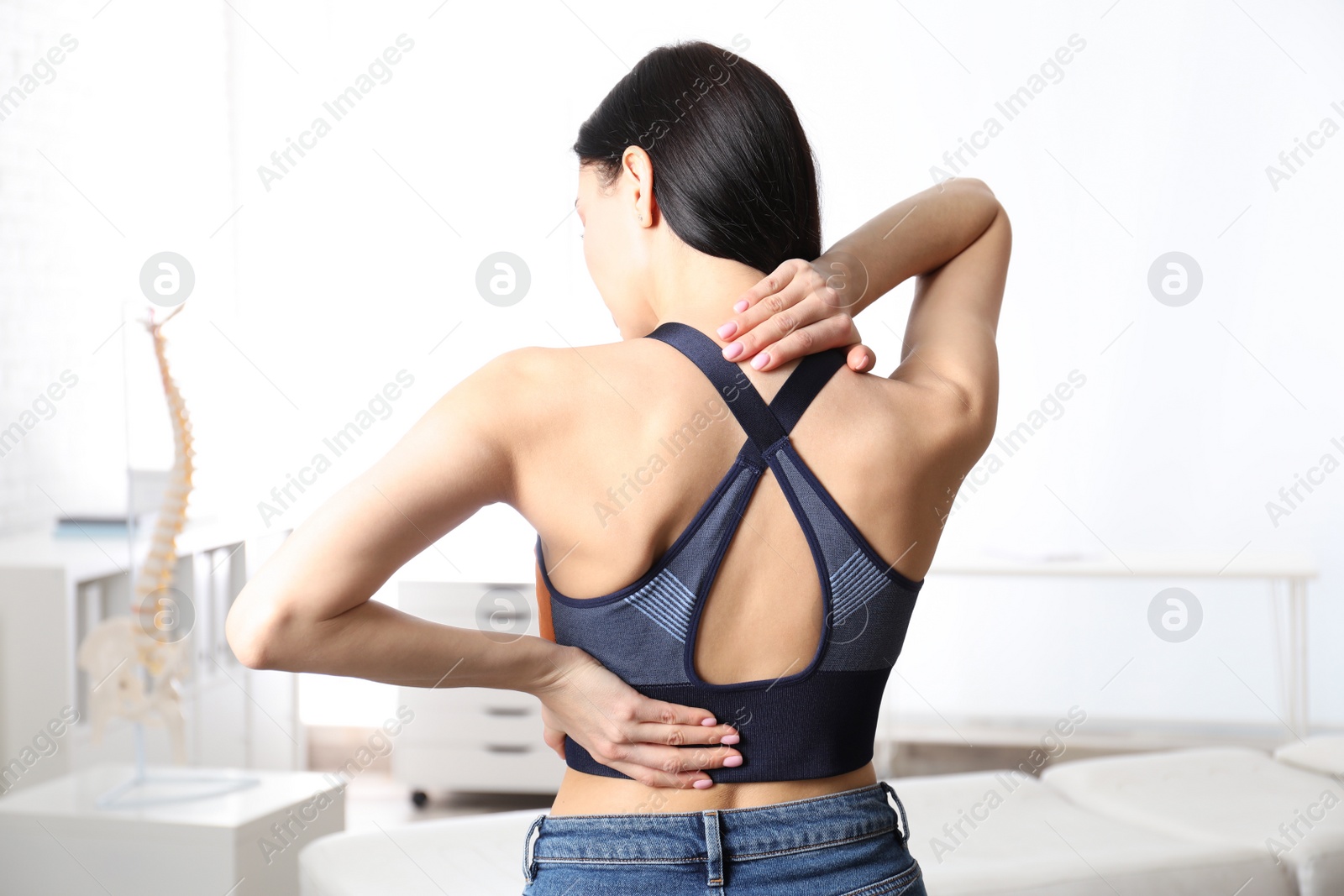 Photo of Woman suffering from pain in back at clinic. Visiting orthopedist