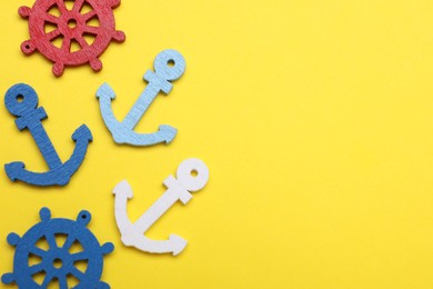 Anchor and ship wheel figures on yellow background, flat lay. Space for text