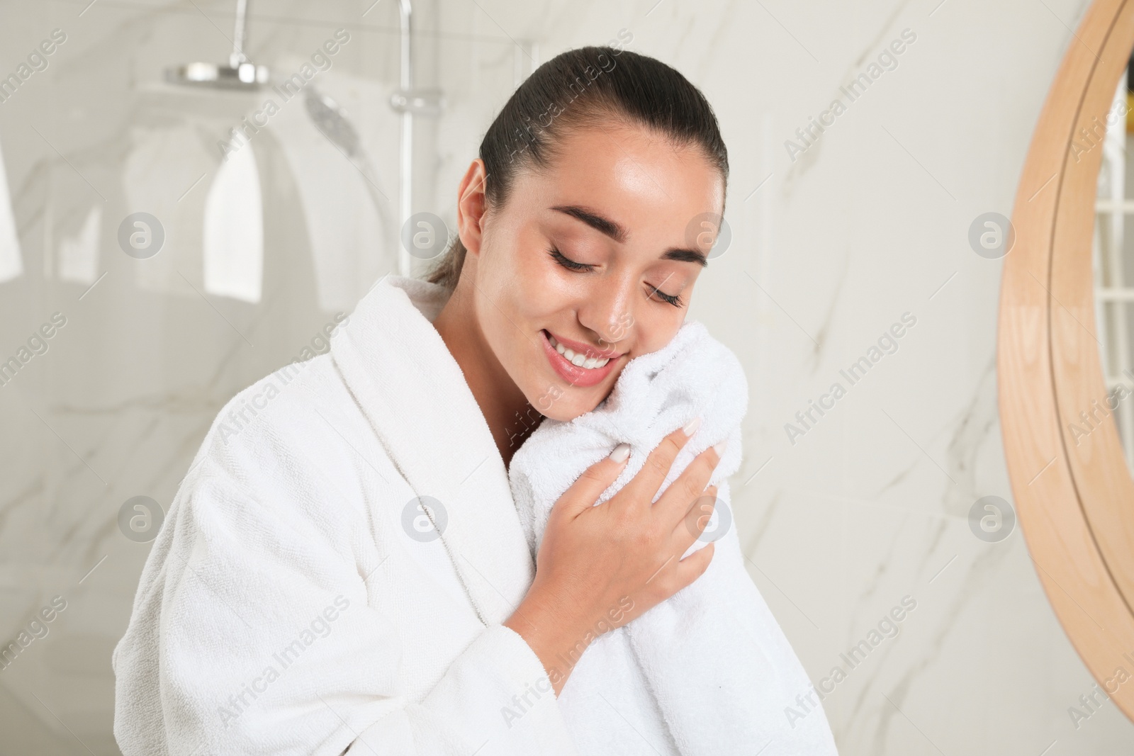 Photo of Beautiful young woman wiping face with towel in bathroom. Facial wash