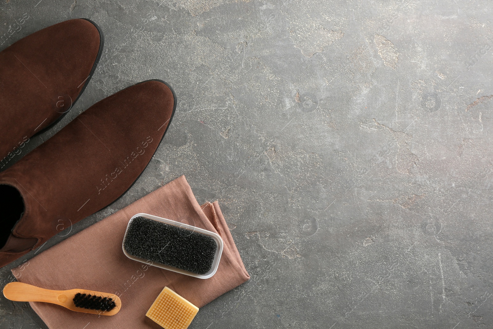 Photo of Stylish footwear with shoe care accessories on grey stone table, flat lay. Space for text