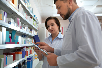 Image of Professional pharmacists near shelves with medicines in modern drugstore