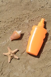 Photo of Blank bottle of sunscreen, starfish and seashell on sand, flat lay