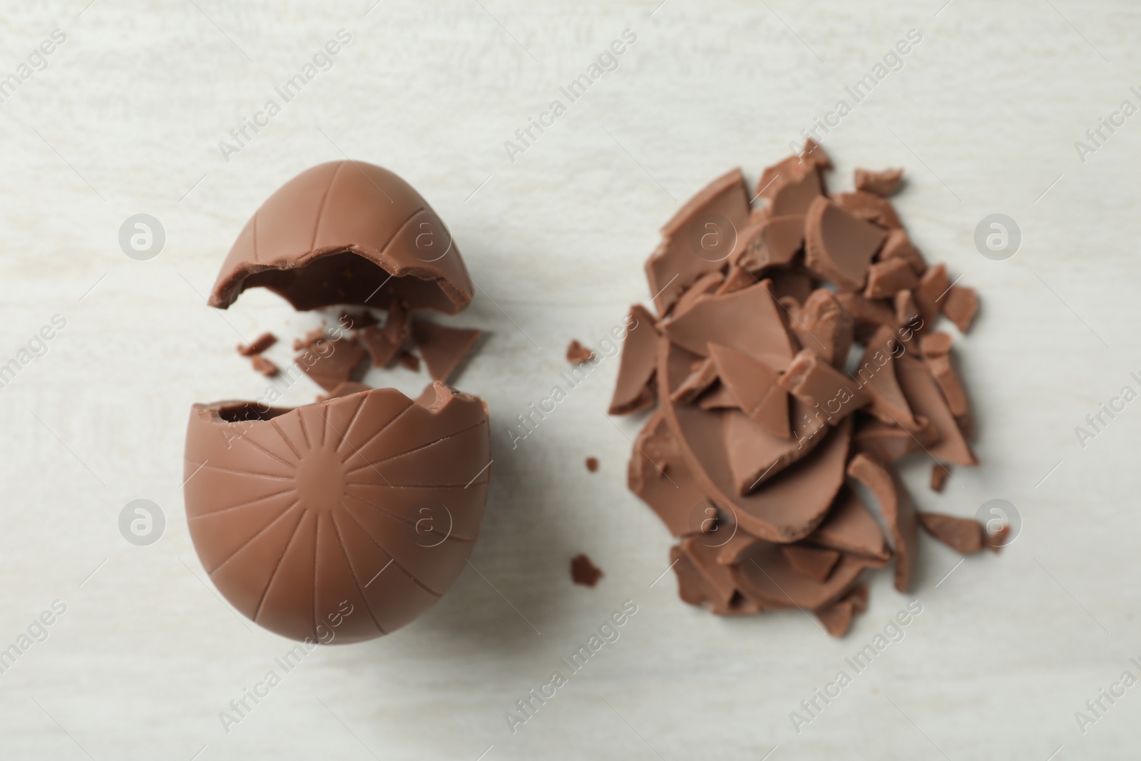 Photo of Broken chocolate eggs on white wooden table, flat lay