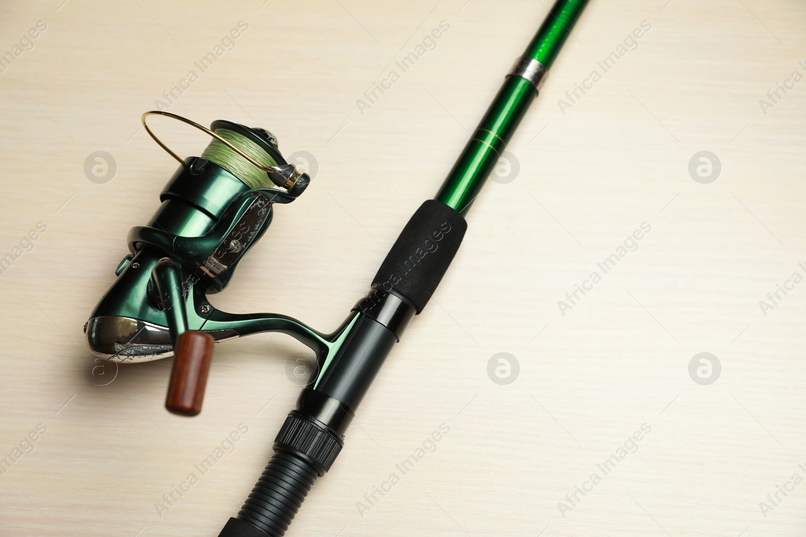 Photo of Modern fishing rod with reel on wooden background, above view. Space for text