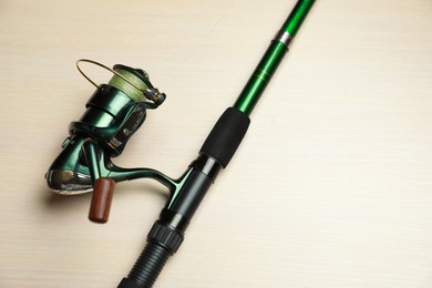 Photo of Modern fishing rod with reel on wooden background, above view. Space for text